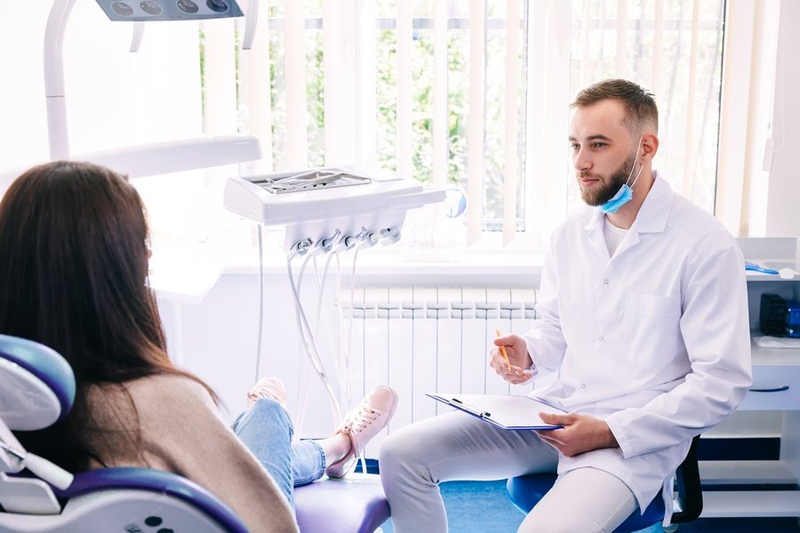 Odontólogo evaluando a una paciente durante una consulta en clínica dental, posible revisión por candidiasis oral.