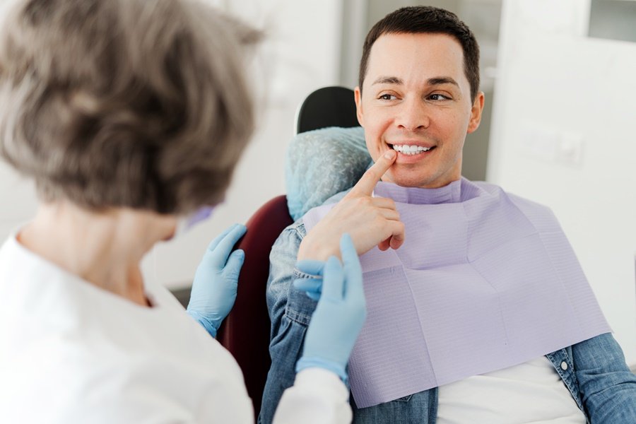 Paciente señalando un diente durante una consulta dental, en una evaluación relacionada con el movimiento dental post-ortodoncia.