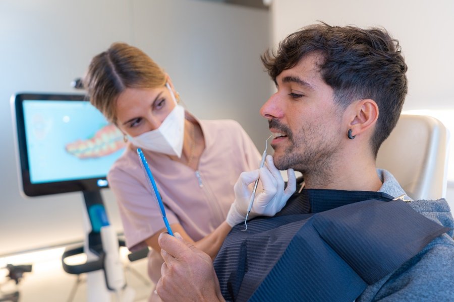 Profesional odontológica explicando a paciente los efectos de la remodelación ósea en la cavidad oral.