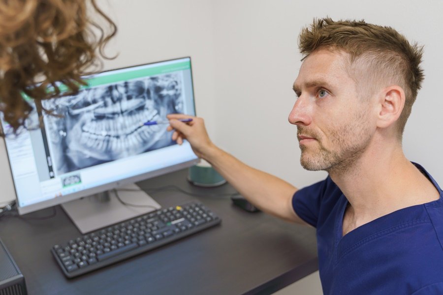 Dentista analizando una radiografía para detectar signos de gingivitis y evaluar el estado de las encías.