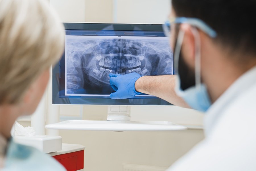 Odontólogo analizando una radiografía para diagnosticar periodontitis y evaluar el estado del hueso alveolar.