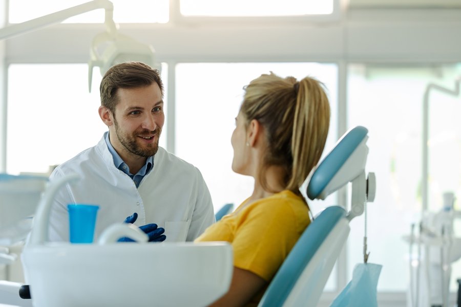 Dentista hablando con una paciente en la consulta. Refleja el papel del profesional en la prevención de problemas relacionados con la genética y la salud dental.