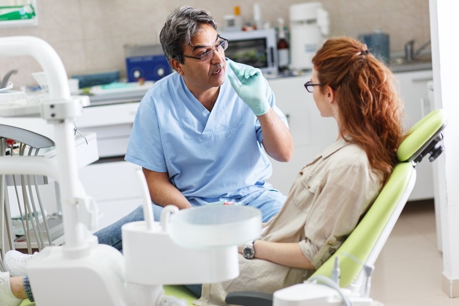 Dentista explicando la función del ligamento periodontal a una paciente adulta en una consulta odontológica.