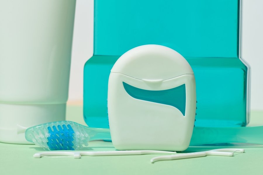 Kit de higiene bucodental con pasta dental, cepillo, colutorio y seda dental sobre fondo claro, representando el uso complementario del dentífrico en el cuidado oral.