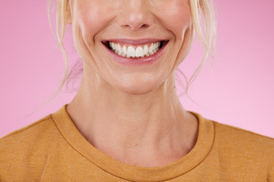 Primer plano de una mujer adulta sonriendo con dientes blancos y sanos, ilustrando los beneficios del calcio en la salud dental.