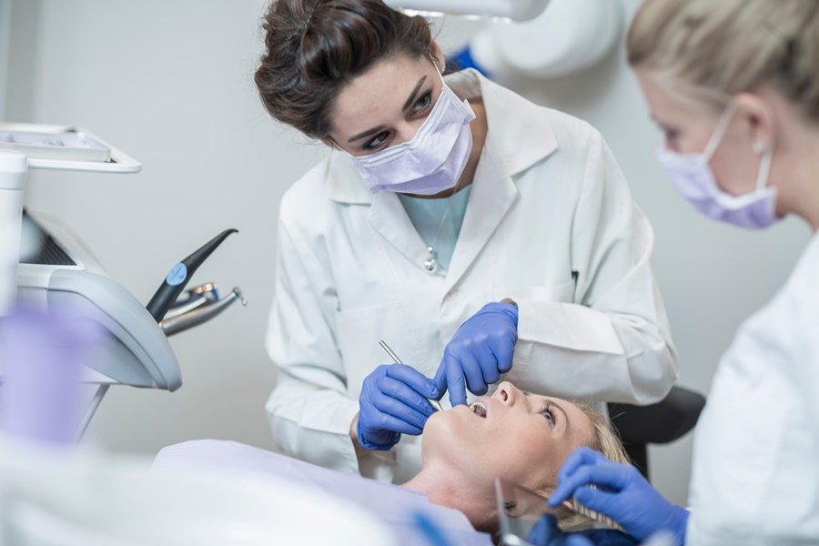 Equipo odontológico examinando la boca de una paciente durante una revisión clínica para detectar signos asociados a vitamina K y sangrado de encías.