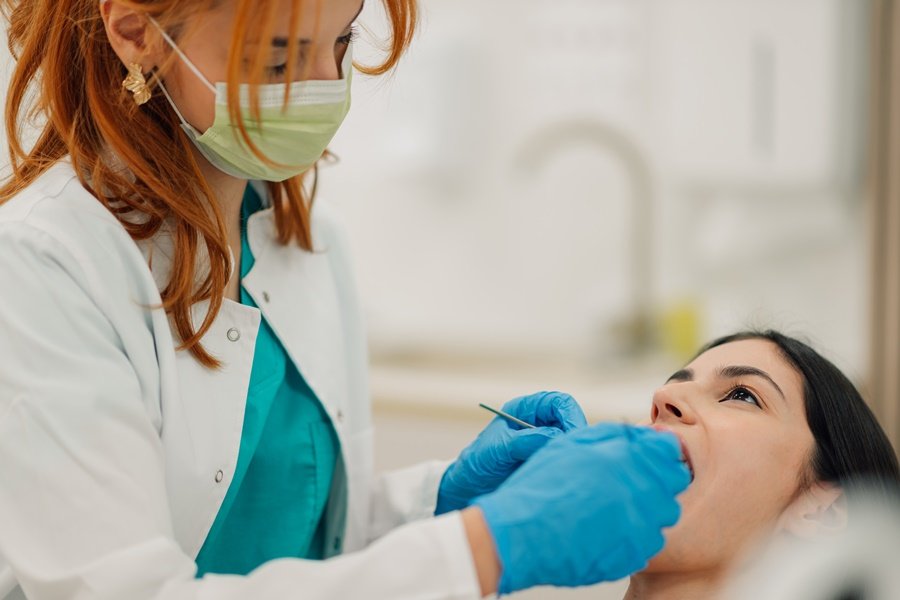 Profesional de odontología observando las encías de una mujer para evaluar posibles problemas de sangrado vinculados a deficiencia de vitamina K.